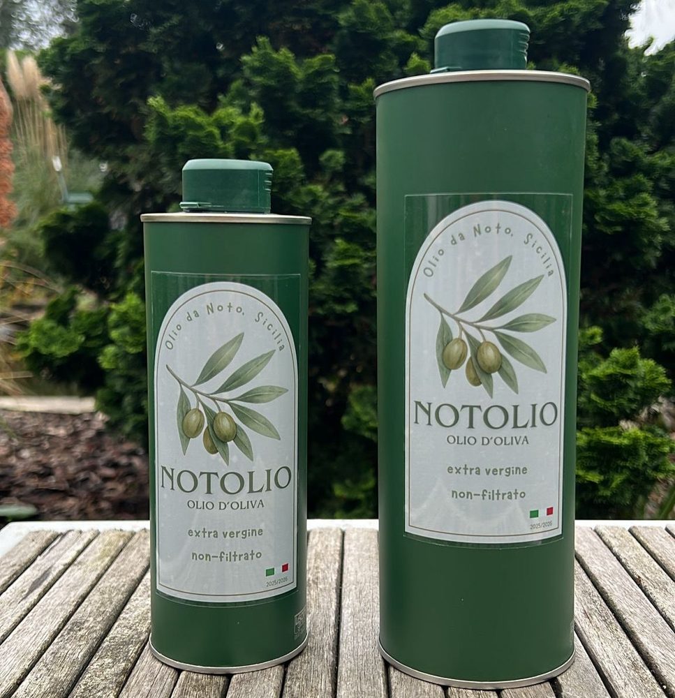 Twee groene blikken Notolio olijfolie, 0,5 en 1 liter, op een houten tafel
